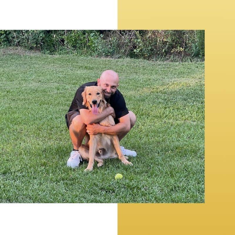 A man holding a dog in the grass